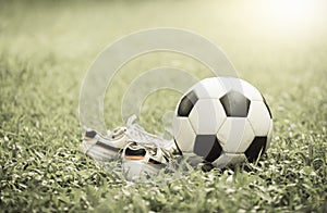 Football on grass and stud shoe on vintage tone