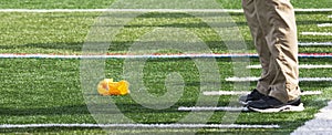 Football officials yellow flag on the ground in front of coaches feet photo