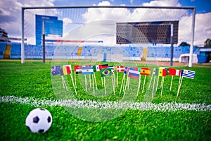 Football pitch, world nations flags, blue sky, football net in background. Sport photo, edit space