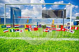 Football pitch, world nations flags, blue sky, football net in background. Sport photo, edit space
