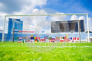 Football pitch, world nations flags, blue sky, football net in background. Sport photo, edit space