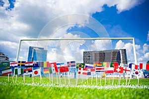 Football pitch, world nations flags, blue sky, football net in background. Sport photo, edit space