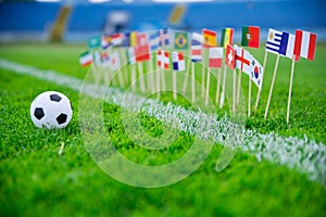 Football pitch, world nations flags, blue sky, football net in background. Sport photo, edit space