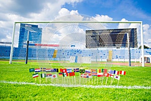 Football pitch, world nations flags, blue sky, football net in background. Sport photo, edit space