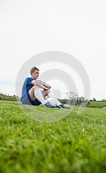 Football player in blue taking a break on the pitch