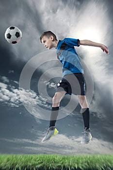 Football player hitting the ball with head on a soccer stadium