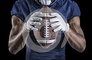 Football Player holding a football tightly at his chest