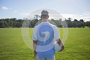 Football player holding soccer in the ground