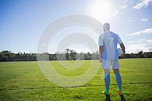 Football player holding soccer in the ground