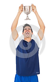 Football player holding up winners cup