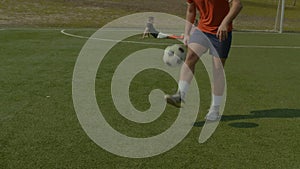 Football player juggling soccer ball on the pitch