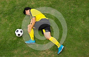 Football player lying injured on the pitch.