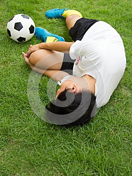 Football player lying injured on the pitch.