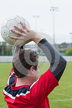 Football player in red throwing from sideline