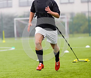 Football player runs while dragging weights behind him. Running with weights soccer training.