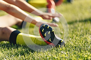Football Player Stretches Sitting on Grass Pitch. Stretching Session After Workout For Footballers