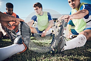 Football player, stretching and feet of men training on a field for sports game and fitness. Closeup on shoes of male