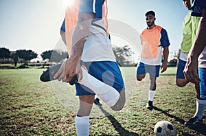 Football player, stretching legs and men training on a field for sports game and fitness. Male soccer team or athlete