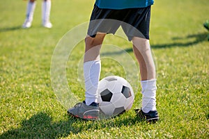 Football players feet close up. Sports training on a grass field background. Boy in a sportswear. Player wearing white football