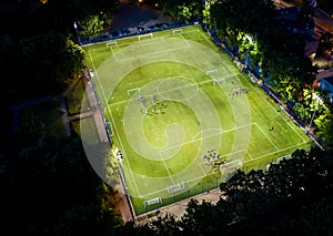 Football players running around the football field. Night workout. Preparation for the match. Aerial shot with a drone from a