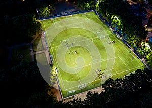 Football players running around the football field. Night workout. Preparation for the match. Aerial shot with a drone from a