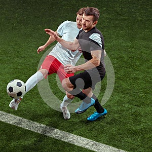 Football players tackling ball over green grass background