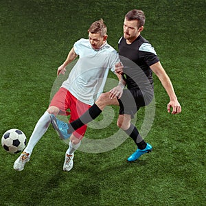 Football players tackling ball over green grass background