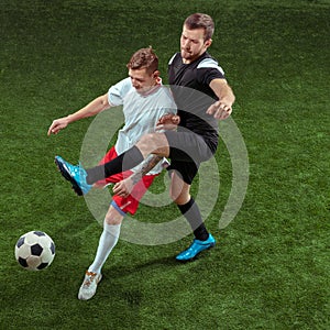 Football players tackling ball over green grass background