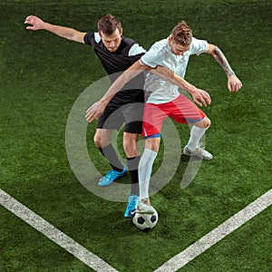 Football players tackling ball over green grass background