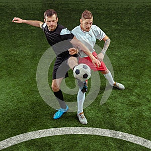 Football players tackling ball over green grass background