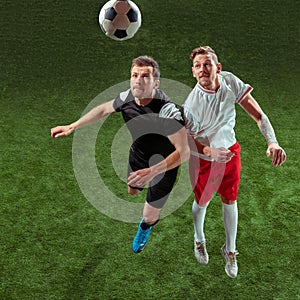 Football players tackling ball over green grass background