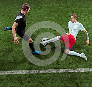 Football players tackling ball over green grass background