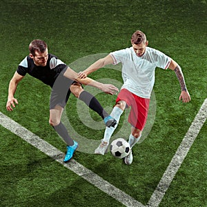 Football players tackling ball over green grass background