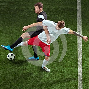 Football players tackling ball over green grass background