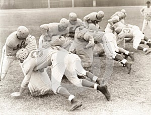 Football players training with tackle bags