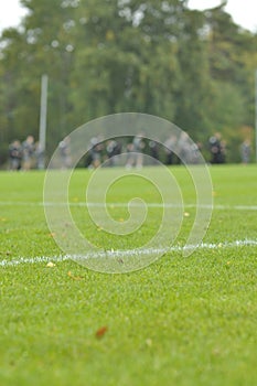 On a football practise and on a green field on a rainy, cold and grey Autumn afternoon with soccer players on a background