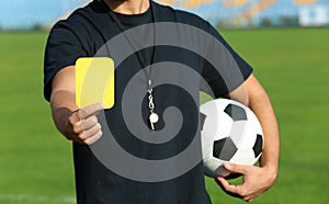 Football referee showing yellow card at stadium