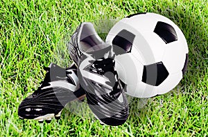 Football shoes and ball on green grass background