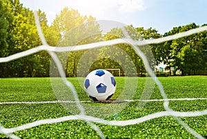 Football soccer ball behind the gate net on field