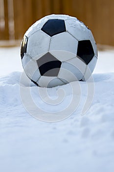 Football, soccer ball on snow with a wooden background