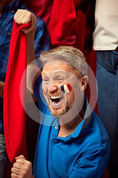 Football, soccer fans watching game. Mature man emotionally cheering up favourite france team. People wearing