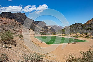 Football and Soccer field inside Mountain and valley along Wadi Sahtan road in Al Hajir mountains between Nizwa and Mascat in Oman photo