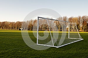 Football or soccer goal post on a green grass pitch in a park. Nobody. Calm mood. Sport theme background. Training ground for