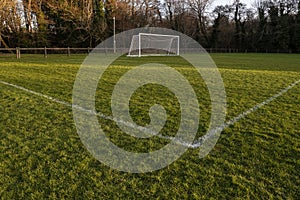 Football or soccer goal post on a green grass pitch in a park. Nobody. Calm mood. Sport theme background. Training ground for