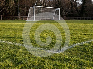 Football or soccer goal post on a green grass pitch in a park. Nobody. Calm mood. Sport theme background. Training ground for