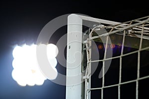 Football or soccer net background, view from behind the goal with blurred stadium and field pitch.