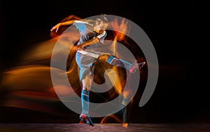 Football or soccer player on black background in mixed light, fire shadows