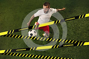Football or soccer player on grass background behind limiting tapes with word Lockdown