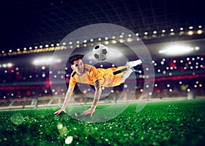 Football striker player with yellow team suit jumps at the soccer stadium photo