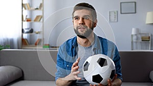 Football supporter attentively watching game on TV, hope of victory championship